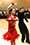 Rickie is in a red dress and Erik is in a black shirt and pants dancing the Paso Doble.