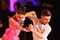 Erik Linder and Rickie Taylor dancing the Paso Doble. Rickie wears a pink dress with flowers and Erik is wearing a white satin shirt.